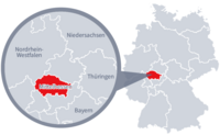 Diese Grafik zeigt eine Karte von Deutschland mit einer detaillierten Ansicht der Region Mittelhessen. Mittelhessen ist in Rot hervorgehoben und liegt im westlichen Teil Deutschlands. Ein Lupensymbol vergrößert diesen Bereich, um die Lage genauer darzustellen. 