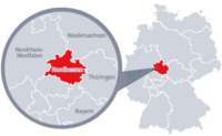 Diese Grafik zeigt eine Karte von Deutschland mit einer detaillierten Ansicht der Region Nordhessen. Nordhessen ist in Rot hervorgehoben und liegt im westlichen Teil Deutschlands. Ein Lupensymbol vergrößert diesen Bereich, um die Lage genauer darzustellen. 
