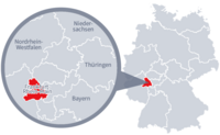 Diese Grafik zeigt eine Karte von Deutschland mit einer detaillierten Ansicht der Region Frankfurt-Rhein-Main. Frankfurt-Rhein-Main ist in Rot hervorgehoben und liegt im westlichen Teil Deutschlands. Ein Lupensymbol vergrößert diesen Bereich, um die Lage genauer darzustellen. 